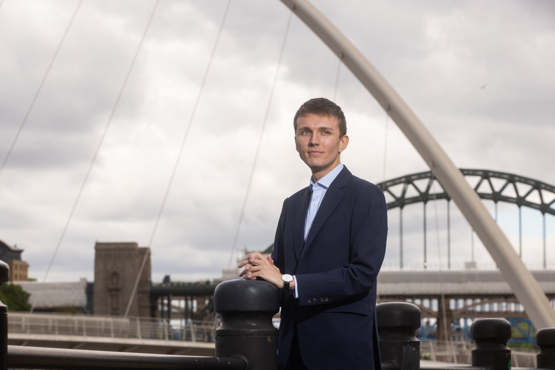 Sebastian Moore leaning on a railing beneath the Gateshead Millennium Bridge