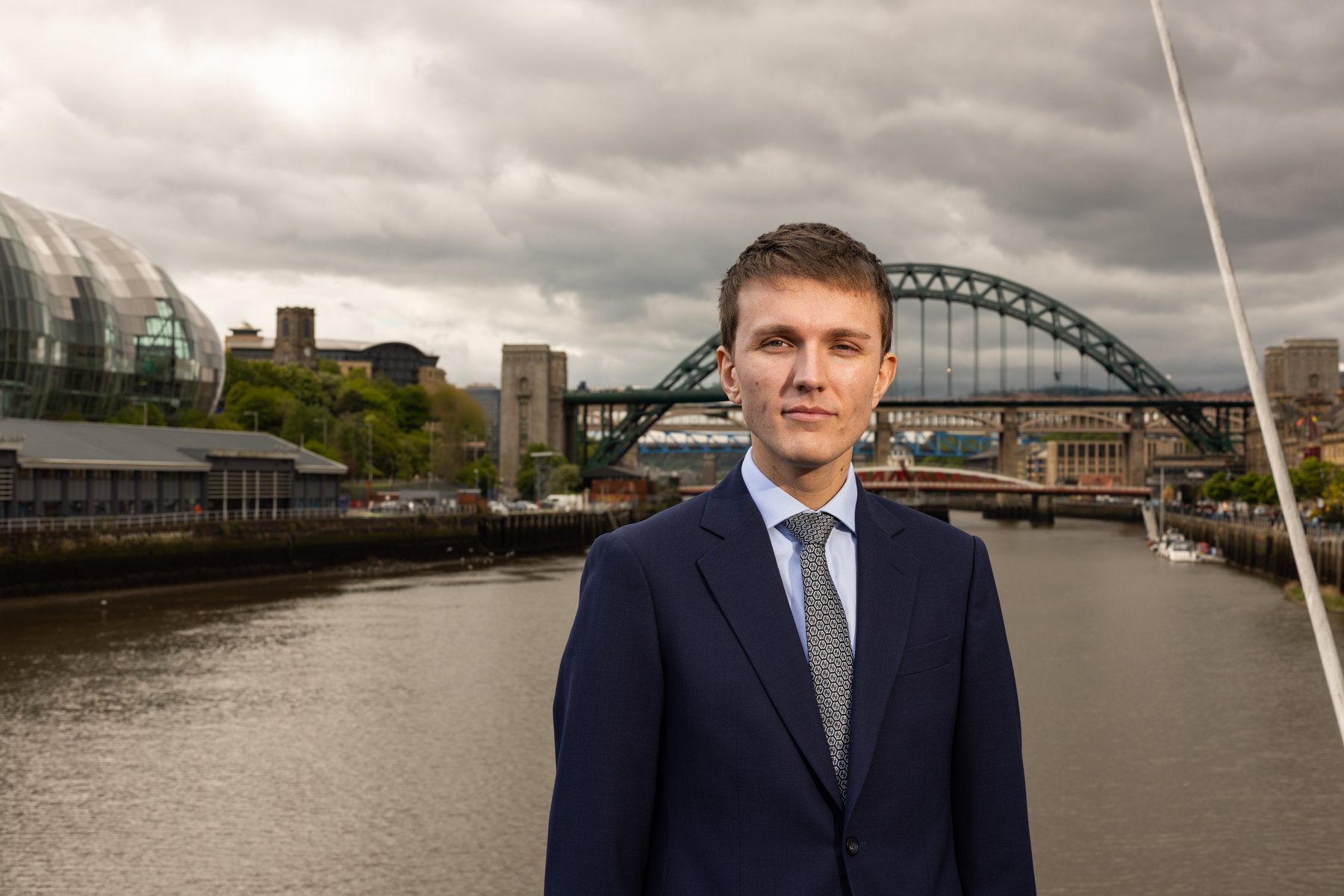 Sebastian Moore standing on Newcastle Quayside with the Tyne Bridge in the background
